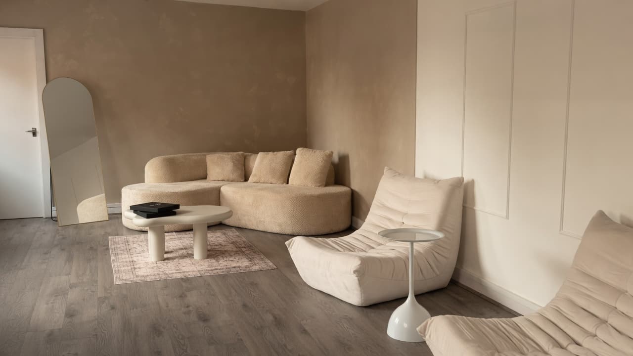 The Content Suite lounge: curved beige sofa, Togo chairs, arched mirror and cream wall panelling