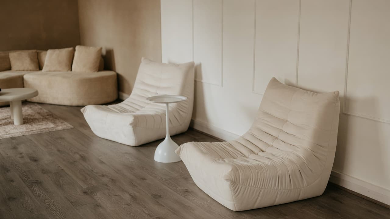 The Content Suite: cream Togo-style floor chairs and a tulip side table against paneled walls