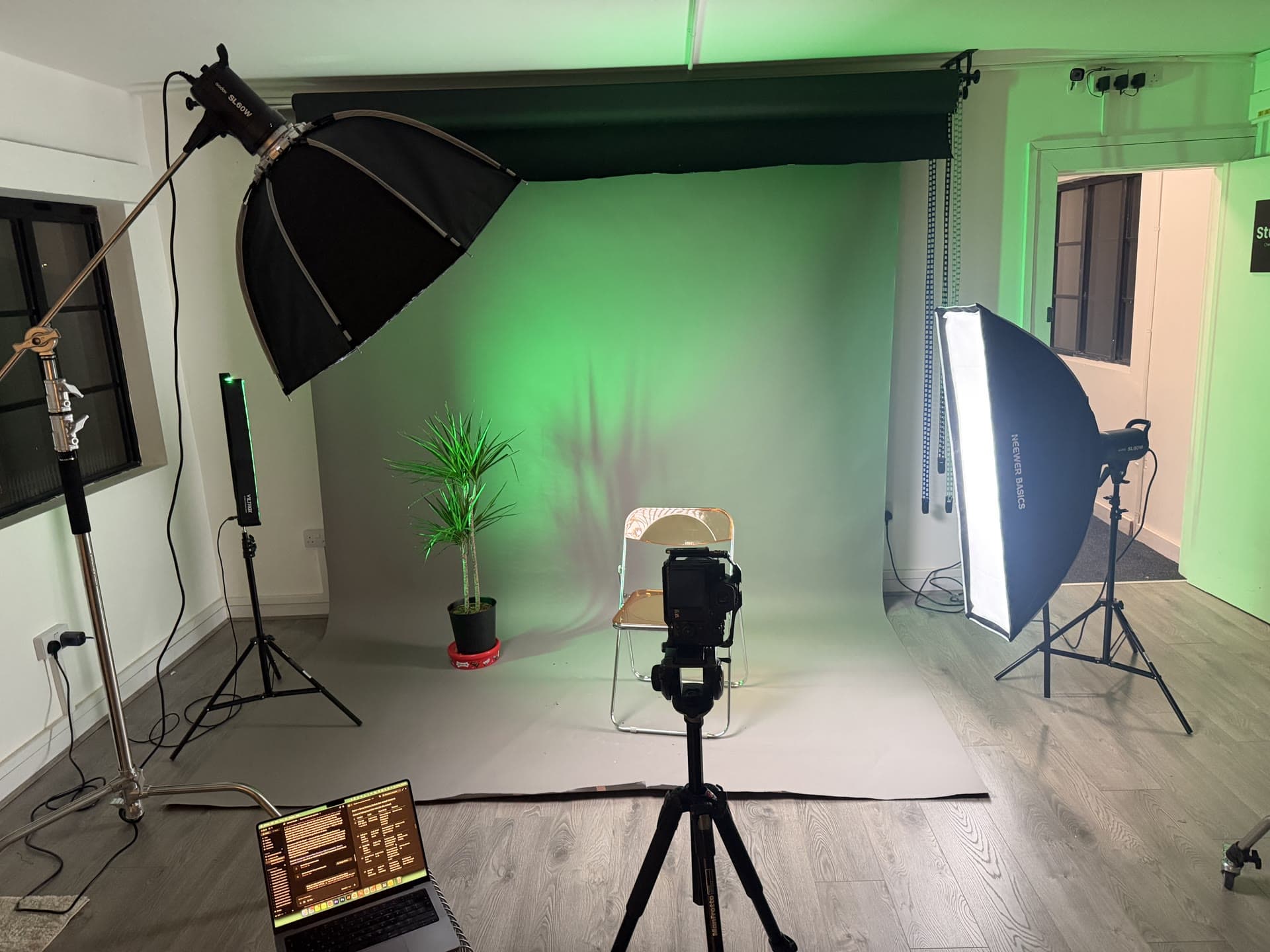 Studio One: grey paper backdrop with a green wash, camera on a tripod, softboxes and a laptop on the floor